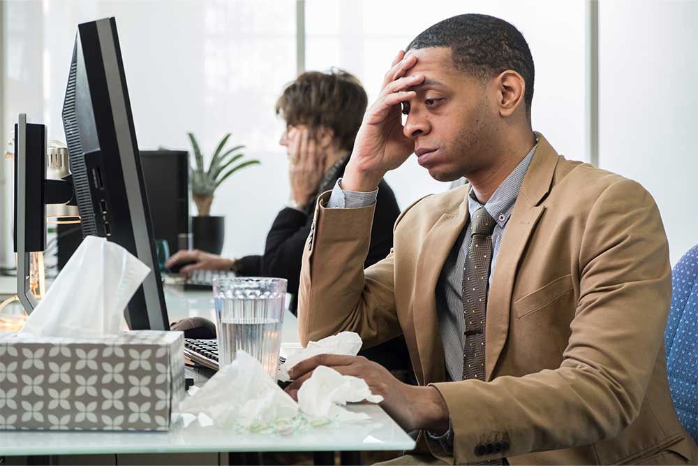 Person working in office sneezes next to coworkers. 